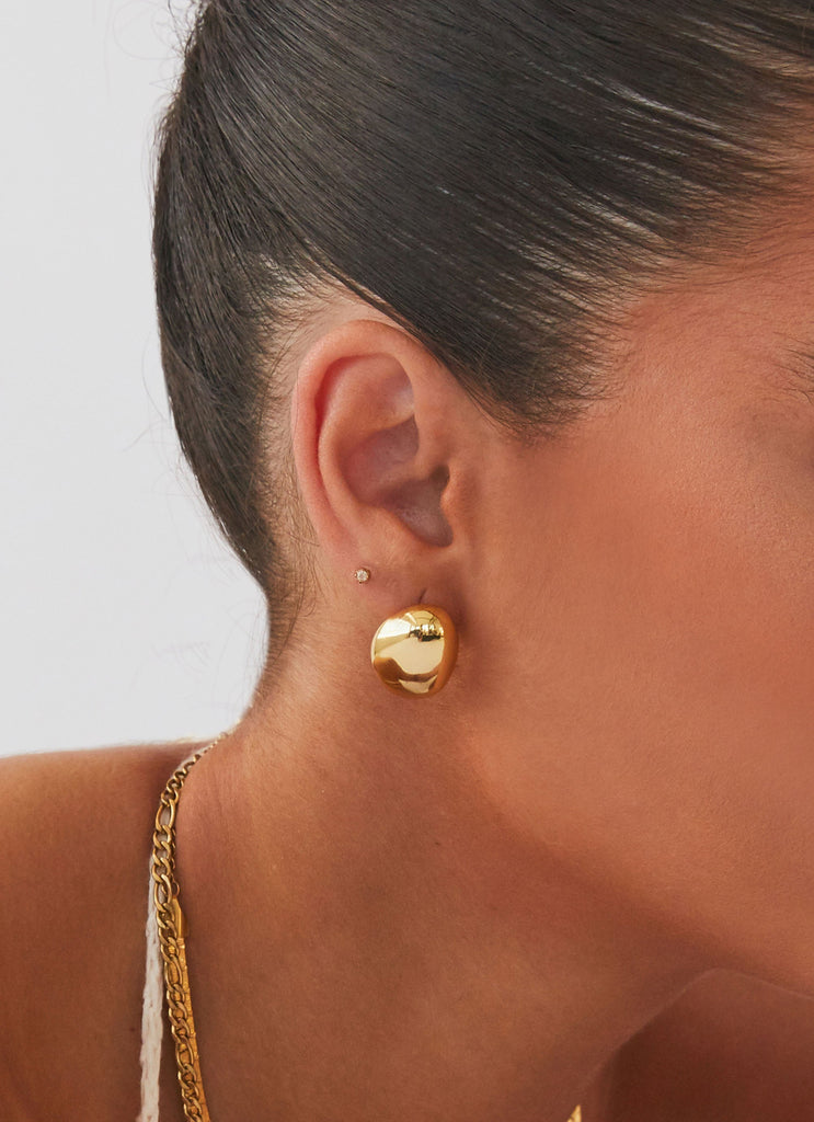 Womens Take A Bow Chunky Stud Earrings in the colour Gold in front of a light grey background