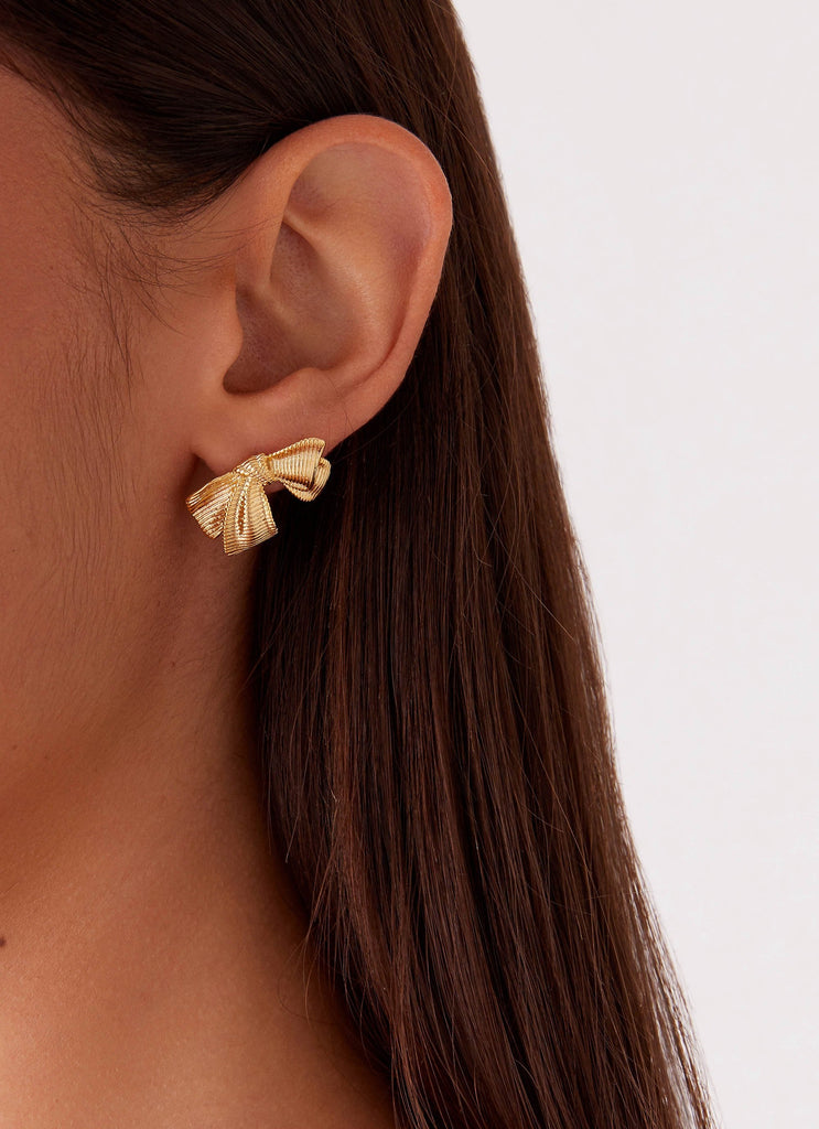 Womens Kiyah Bow Earrings in the colour Gold in front of a light grey background