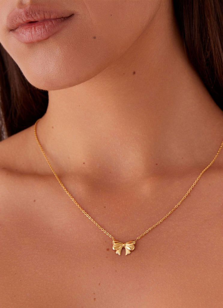 Womens Sweetheart Bow Necklace in the colour Gold in front of a light grey background