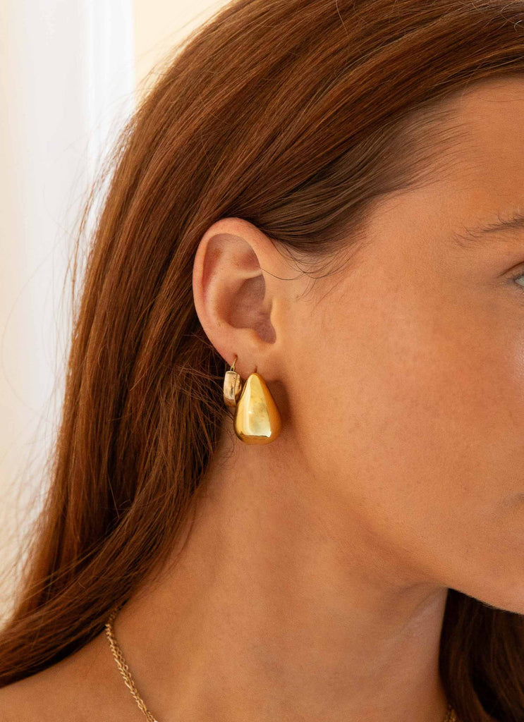 Womens Big Energy Earrings in the colour Gold in front of a light grey background